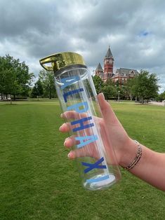 a hand holding a water bottle with the word fix on it in front of a grassy field