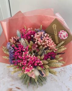 a bouquet of flowers sitting on top of a table next to a brown paper bag