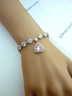 ORIGINAL DESIGN BY JCBRIDAL JEWELRY.This bracelet features a halo light pink trillion cubic zirconia with multi round drops cubic zirconia, finished with a lobster clasp.Size: 7.2 inches , or 180 mm (2 inches extension chain can be provided upon request)Matching Earrings and Necklace:Listing: https://www.etsy.com/listing/167217887/jcbridal-original-design-wedding-bridalListing: https://www.etsy.com/listing/167217947/wedding-earrings-bridal-earrings-uniqueFor more gemstone jewelry, please visit m Pink Crystal Wedding Bracelets, Pink Sparkling Stones Bracelet For Wedding, Pink Wedding Bracelets With Sparkling Stones, White Sterling Silver Crystal Bracelet For Wedding, Sterling Silver Round Charm Bracelet For Wedding, Wedding Tennis Bracelet With Hand-set Crystals, Wedding Tennis Bracelet With Hand Set Crystals, Wedding Hand-set Crystal Tennis Bracelet, Wedding Crystal Bracelet With Sparkling Stones In Sterling Silver