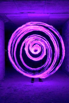 a person standing in front of a purple circular object with light painting on it's side