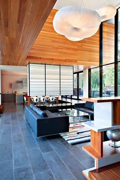 a living room filled with lots of furniture and large windows on top of the ceiling