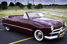 a purple convertible car parked in a parking lot next to a red sign that says 94 ford custom convertible