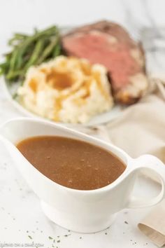 a white gravy dish with meat and vegetables on the side