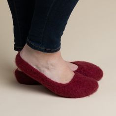 a woman's feet wearing red slippers and jeans