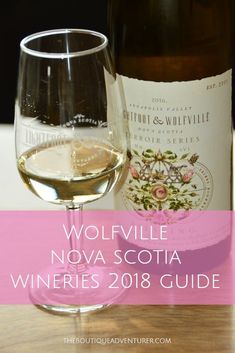 a glass of wine sitting next to a bottle on top of a wooden table with the words wolfville nova scotta wines 2018 guide