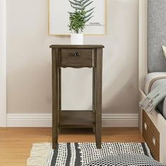 a small wooden table with a plant on it in a bedroom next to a bed