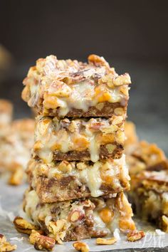 a stack of dessert bars sitting on top of a piece of tin foil covered in nuts