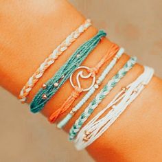 a woman's arm with four different bracelets on top of each other,