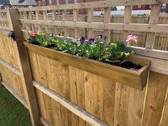 a wooden fence with flowers growing in the planter box on it's side