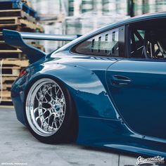 a blue sports car with chrome rims parked in front of a pallet rack