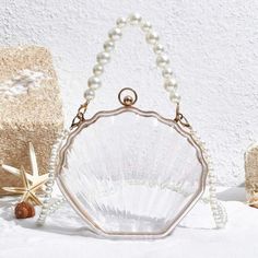 This Transparent Pearl Portable Shell Shape Bag is perfect for your vacation needs. With its chic and trendy design, you can easily carry your essentials in style. The pearl strap adds a touch of elegance, while the transparent material makes it easier to find what you need. Don't sacrifice fashion for convenience - have both with this mini portable bag. Material: Acrylic Trendy Clear Shoulder Bag For Beach, Trendy Clear Shoulder Bag For The Beach, Clear Shoulder Bag For Beach, Trendy Beach Bags With Clear Strap, Trendy Beach Bag With Clear Strap, Summer Beach Shoulder Bag With Clear Strap, Beach Shoulder Bag With Clear Strap, Elegant Beach Bag With Pearl Handle, Summer Evening Bag Made Of Pearl