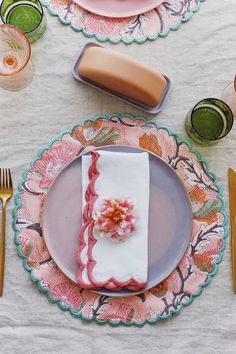 the table is set with pink plates and silverware