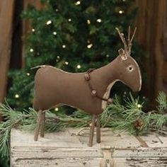 The Stiffened Standing Reindeer is a decorative primitive plush reindeer figurine made of stiffened fabric with a rustic brown finish. The reindeer has bead eyes, twig legs and antlers, and wears a brown wreath collar with rusted jingle bells. Display this reindeer standing on a shelf or tabletop to bring a primitive country touch to the home during the Christmas season. Measures 10” high by 10” wide by 3” deep. Brown Wreath, Primitive Christmas Crafts, Primitive Ornaments, Reindeer Figure, Primitive Christmas Decorating, Primitive Christmas Decor, Wood Ceiling Lights, Primitive Wood Signs, Primitive Candles