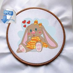 a cross stitch bunny is sitting on the ground