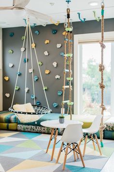 a living room filled with lots of furniture and hanging decorations on the wall above a white table