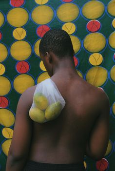 a man standing in front of a colorful wall with fruit on his chest and back