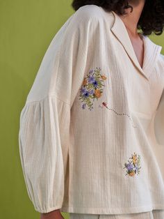 Relaxed fit, long puff sleeve, v-neck shirt crafted in double gauze organic cotton fabric that's embroidered with botanic-inspired motifs. This classic, staple shirt is so versatile and can be endlessly mixed-and-matched to create a fresh outfit each time you put it on. Techniques Used: Hand Embroidery. #cuteeverydayoutfits #prettyoutfits #falloutfitswomen #shirtdesign #topsforwomen Spring V-neck Blouse With Chikankari Embroidery, Fall Cotton Blouse With Embroidered Cuffs, Long Sleeve Cotton Blouse With Embroidered Cuffs, Cotton Shirt With Gathered Long Sleeves, Casual Cotton Blouse With Embroidered Cuffs, Cotton Blouse With Embroidered Cuffs, Bohemian Cotton Blouse With Embroidered Cuffs, Spring Linen Top With Chikankari Embroidery, Embroidered Linen Long Sleeve Shirt