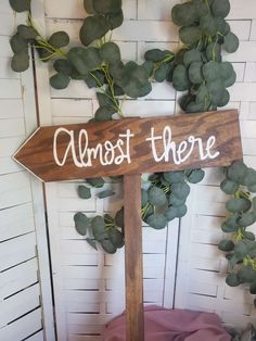 a wooden sign that says almost there next to a plant with green leaves on it