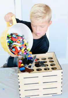 a young boy is playing with legos in a box