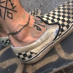 a person's feet with tattoos on them and checkered slip - ons