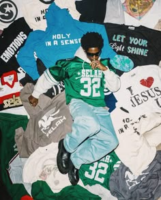 a man laying on top of a pile of t - shirts and other clothing items