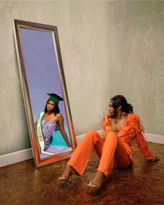 a woman sitting on the floor in front of a mirror with an image of herself