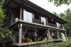 a large house sitting on the side of a lush green forest covered hillside next to trees