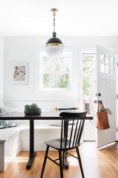 a dining room table with two chairs and a bench in front of the door to another room