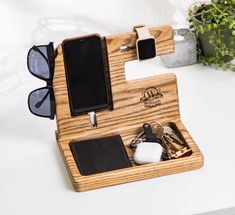 a wooden case with sunglasses, cell phone and keys in it on a white surface