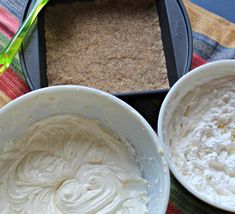 two bowls filled with white frosting on top of a table