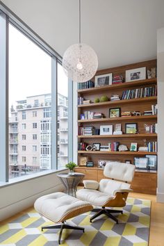 a living room with a large window and a chair in front of the bookshelf