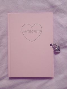 a pink notebook with a heart on it and the words my secrets written in silver