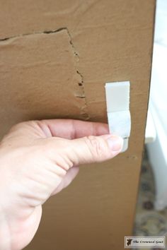 a person holding a piece of paper in front of a cardboard box that has been torn off