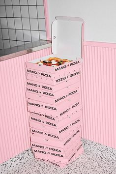 a stack of pizza boxes sitting on top of a floor next to a pink wall