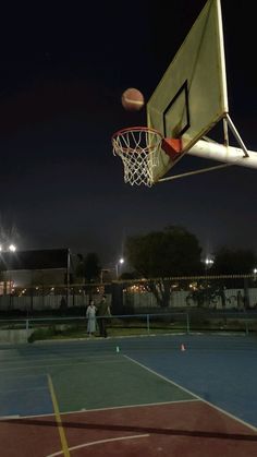 an outdoor basketball court at night with people playing