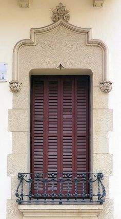 an ornate balcony with wrought iron railing and red shutters