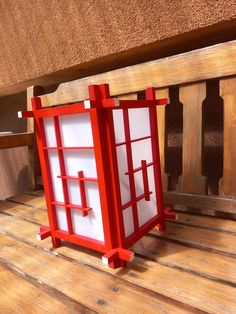 a small red and white object sitting on top of a wooden floor next to a bench