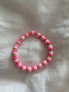 A pink and gold clay beaded bracelet. Fits most as it is stretchy.Handmade Pink Flat Bead Bracelet Ideas, Clay Bead Bracelet Pink, Bracelet Ideas Pink, Pink Clay Bead Bracelet Ideas, Pink Bracelet Ideas, Pink Clay Bead Bracelet, Cute Bracelet Ideas Clay Beads, Ideas Pulseras, Preppy Bracelet Ideas