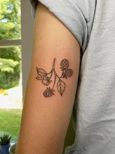 a woman with a tattoo on her arm holding a cup and some flowers in front of her