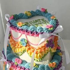 a three layer cake decorated with flowers and ribbons