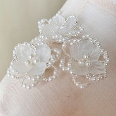 two white flowers and pearls on a pillow