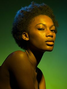 a woman with an afro is posing for a photo in front of a green background