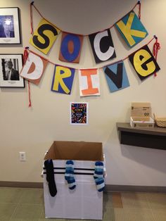 a cardboard box with socks on it sitting in front of a wall decorated with pictures and letters