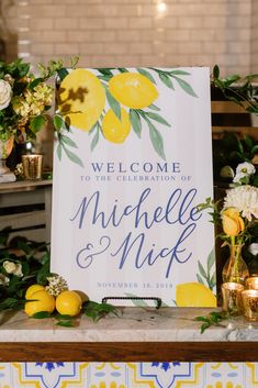 a welcome sign sitting on top of a table with lemons and flowers around it