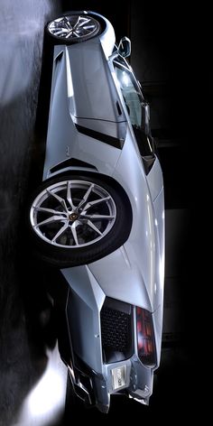 the rear end of a silver sports car with wheels on it's rims