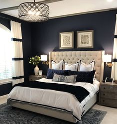 a bedroom with blue walls, white bedding and black accents on the headboard