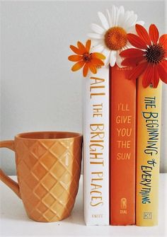 two books and a coffee mug sitting next to each other on a white counter top