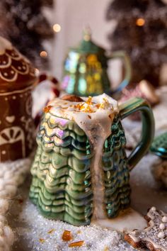 a green and white coffee mug sitting on top of snow covered ground