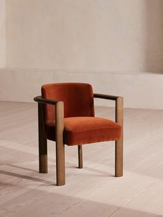 an orange chair sitting on top of a hard wood floor next to a white wall