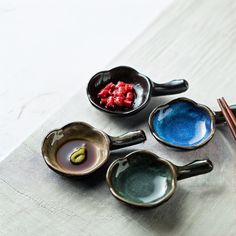 four bowls with spoons and chopsticks on a table